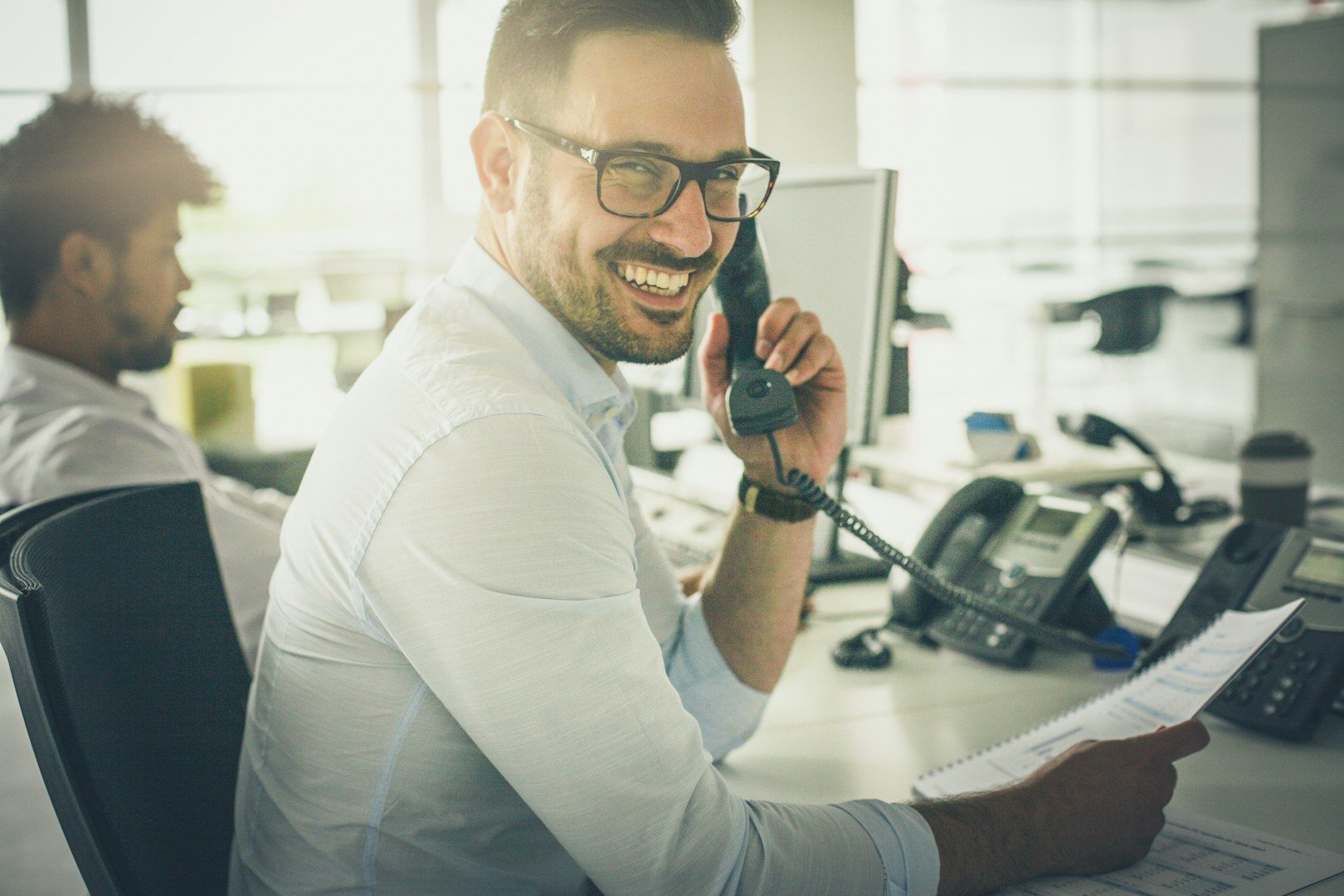 Mann am Telefon im modernen Büro - Unsplash Bild Mann am Telefon mit Brille, lächelnd, in einem modernen Büro.
