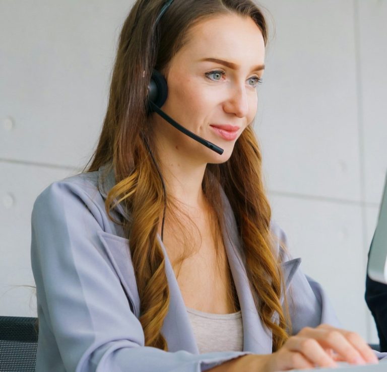 Frau mit Headset im modernen Büro - Unsplash Bild Frau mit Headset tippt an einem Computer in einem modernen Büro.